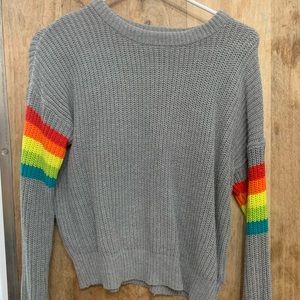 Gray knit sweater with rainbow sleeves.